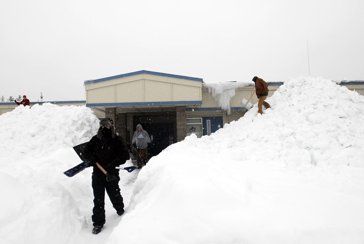 Workers from Eastside Excavation scramble down from the roof after shoveling off Athol Elementary on Tuesday. The group was headed to Garwood Elementary next.  (Jesse Tinsley / The Spokesman-Review)