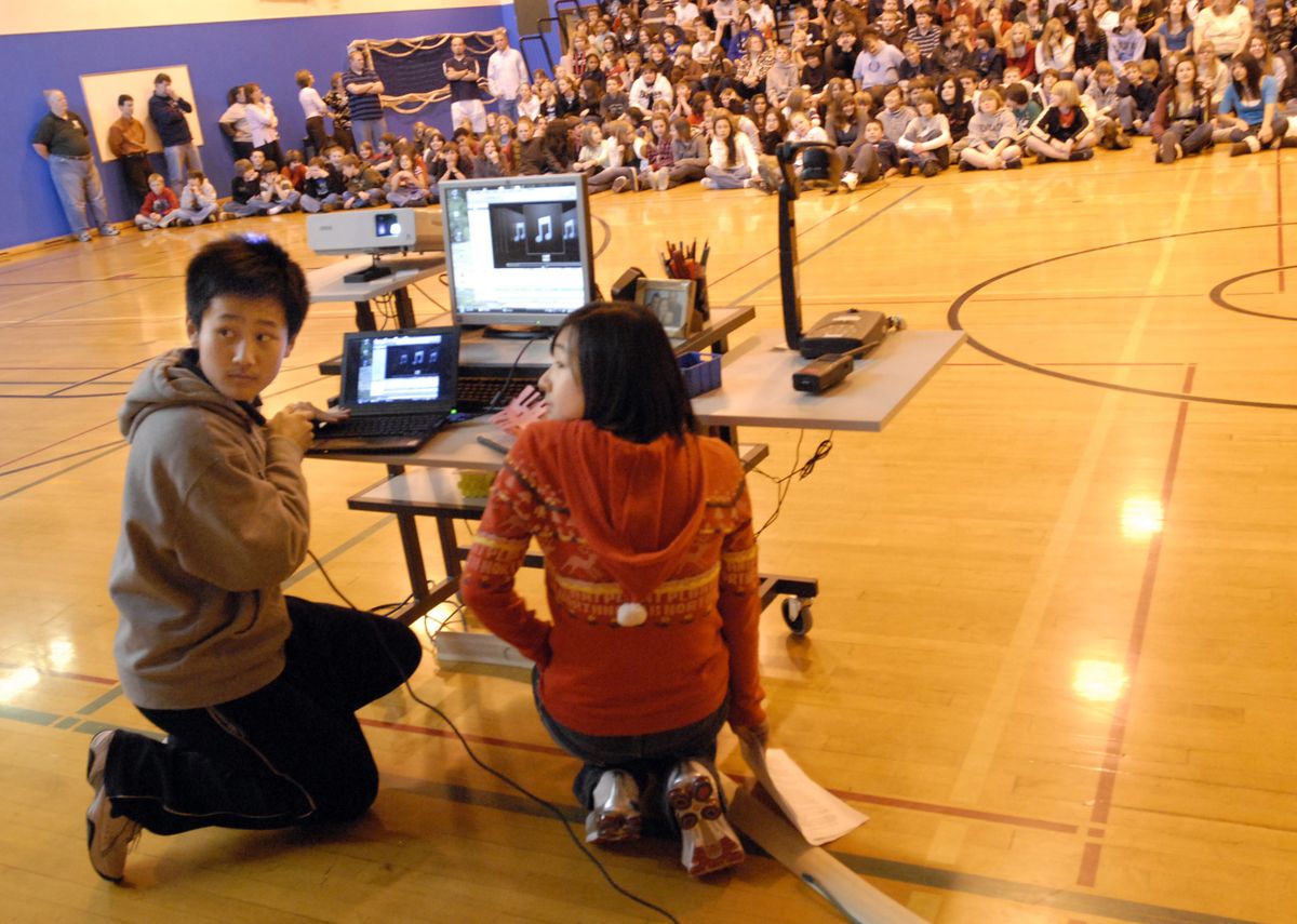 Bryan Wang holds the  microphone to the computer speaker to amplify  traditional Chinese music  student Lily Fu was playing to the North Pines Junior High student body during a cultural assembly marking the end of the exchange student’s visit.  (J. BART RAYNIAK / The Spokesman-Review)