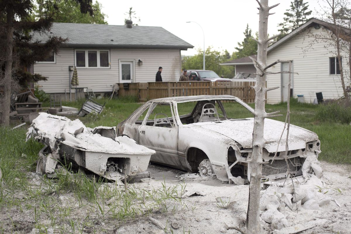 A burned-out car and boat sit in a yard as residents look around their house as they re-enter their home in Fort McMurray, Alberta,  on Wednesday, June 1, 2016. Residents started to return to the fire-damaged city in northern Alberta on Wednesday, but officials have warned that they should not expect everything to be running normally right away. (Jason Franson / Canadian Press via AP)