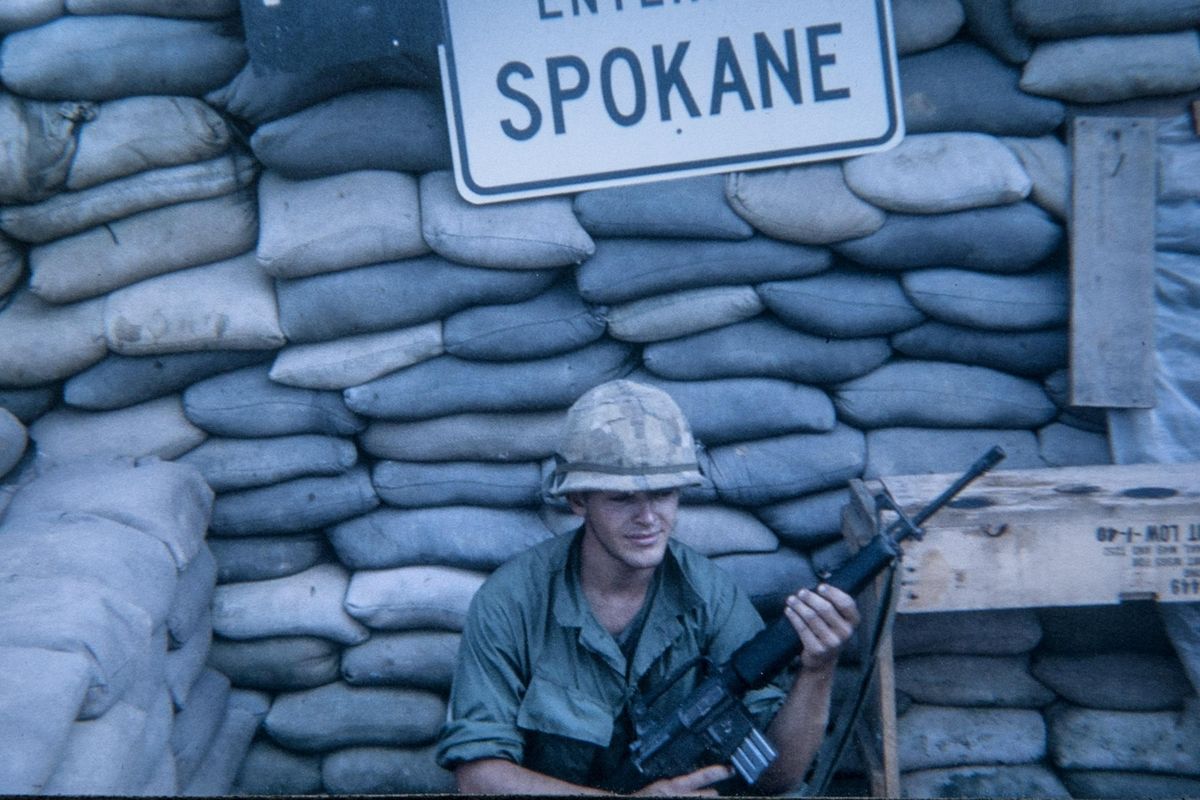 Steve Melville poses with the Entering Spokane sign in Vietnam. Melville’s sister sent the sign, which was made by the street department, when he was serving in a unit with a few other men from Spokane. (Courtesy photos)