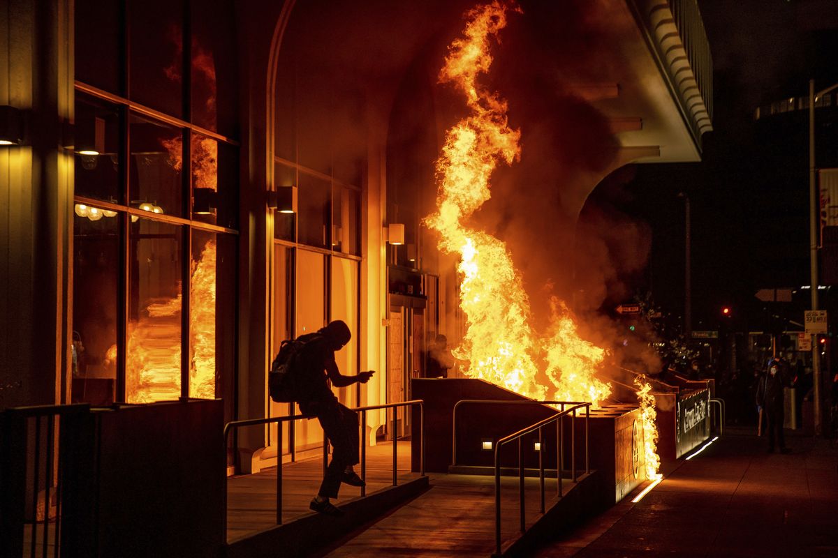 Demonstrators set fire to the front of the California Bank and Trust building during a protest against police brutality in Oakland, Calif., Friday, April 16, 2021. (Ethan Swope)