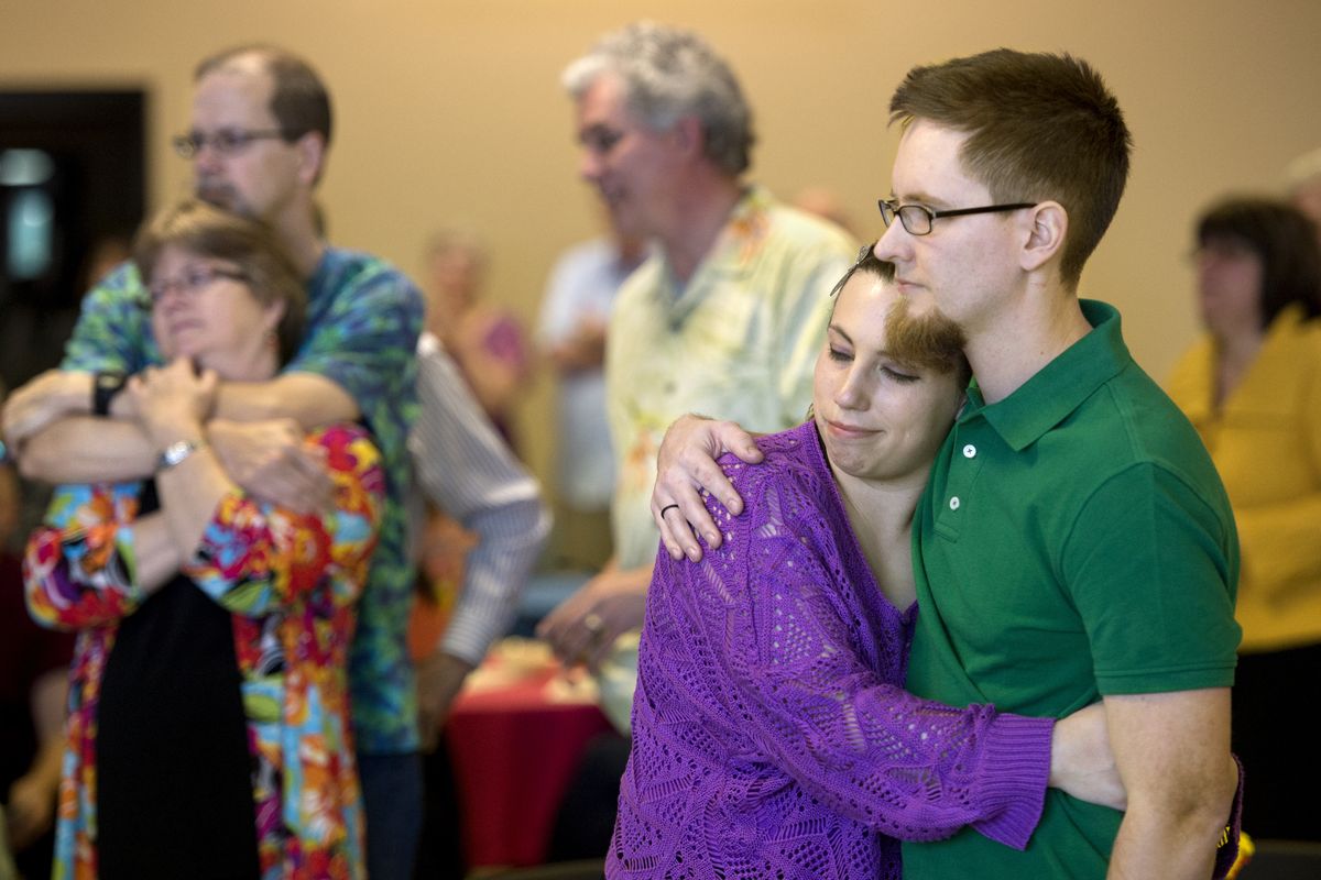 Ryan Smith, right, embraces his girlfriend, Tara Casterlin, during a memorial celebration for his father, Kevin Smith, on Friday at New Life Church. At left are Kevin’s close friends Doug and Liza Keithley, of Boise, and Alan Edel, center, of San Jose, Calif. (Dan Pelle)