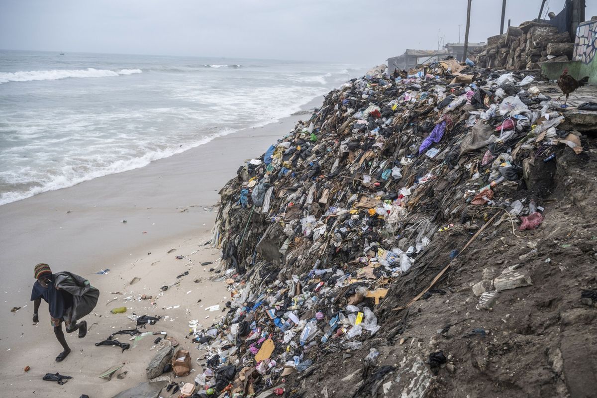 A trash picker walks by piles of garbage and textile waste on the shoreline at Chorkor beach in Accra, Ghana, on Sept. 16.  (Andrew Caballero-Reynolds/Bloomberg)
