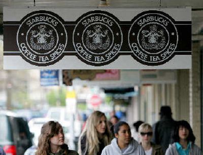 Signs for the original Starbucks coffeehouse store hang with the original logo in the Pike Place Market in Seattle. 
 (Associated Press / The Spokesman-Review)