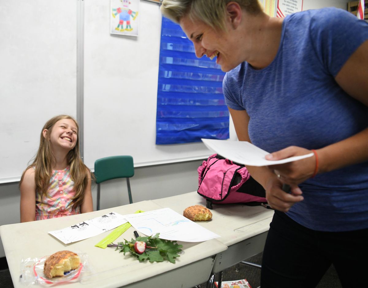 Fourth-grader Arianna Carter laughs with Erika Prins Simonds about the comic strip she wrote for the West Central Express newspaper in a classroom at Holmes Elementary Wednesday, May 30, 2018. The Express is an after-school activity where kids write stories and do other journalism-related learning after school. (Jesse Tinsley / The Spokesman-Review)
