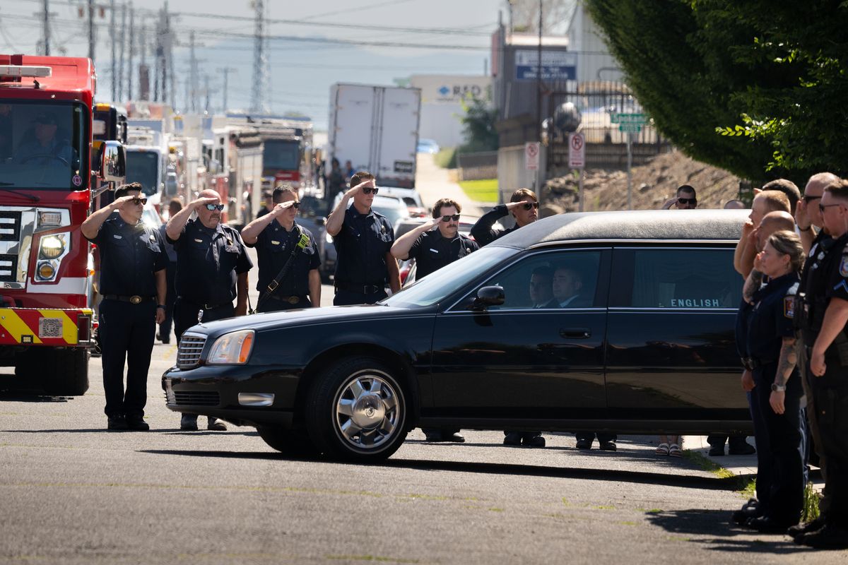 A hearse carrying one of two firefighters is saluted by first responders as it leaves the Spokane County Medical Examiner’s Office on Tuesday morning. Around 300 first responders from agencies across the region, their families and community members lined the streets around the Medical Examiner’s Office just before the procession for two firefighters killed in the line of duty got underway. (Colin Mulvany/The Spokesman-Review)