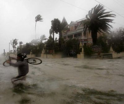 
Jaime Trujillo carries his bike across a flooded street in Key West, Fla., after the eye of Hurricane Dennis passed west of the island on Saturday. 
 (Associated Press / The Spokesman-Review)