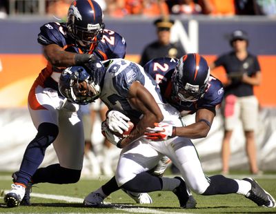 Seattle  Seahawks wide receiver Ben Obomanu (87) is tackled by Denver Broncos' Renaldo Hill (23) and Champ Bailey (24) as he crosses the goal line for a touchdown during the second half of an NFL football game Sunday, Sept. 19, 2010, in Denver. Denver beat Seattle 31-14.  (Matt McClain / Associated Press)