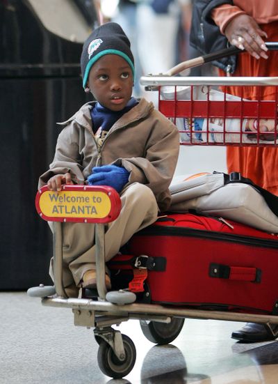 A child rides on a luggage cart at Hartsfield Jackson Atlanta International Airport in Atlanta in 2005. Cart use and revenue are declining because of baggage fees and wheeled luggage. (Associated Press)