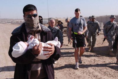 
Charlie Company soldiers escort 3-month-old Noor al-Zahra and her father, holding Noor, as they leave Camp Liberty near Baghdad on Friday. 
 (Associated Press / The Spokesman-Review)
