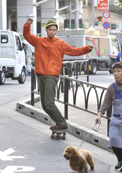 Above: Yutaka Makino, a 28-year-old musician and part-time maintenance worker, zips around his Tokyo neighborhood on a skateboard. Like many young adults in Japan, Makino has decided the cost of car ownership is too high.   At left: Aya Asano, bottom, and her sister Nagisa, holding their dogs,  check out a new car at Honda dealership in Kawasaki, Japan, that caters specially to dog owners. Associated Press photos (Associated Press photos / The Spokesman-Review)