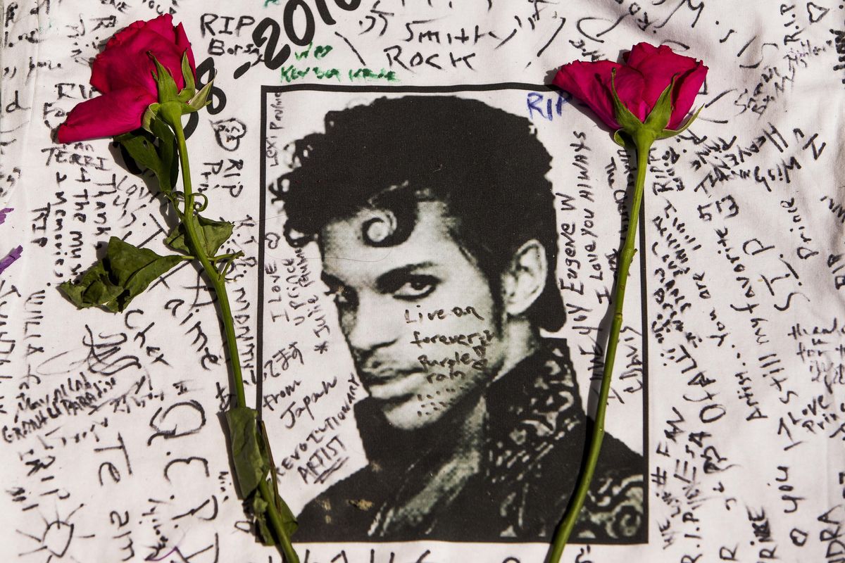 Flowers lie on a T-shirt signed by fans at a makeshift memorial for musician Prince outside the Apollo Theater in New York on April 22. The singer died at age 57. (Andres Kudacki / AP)