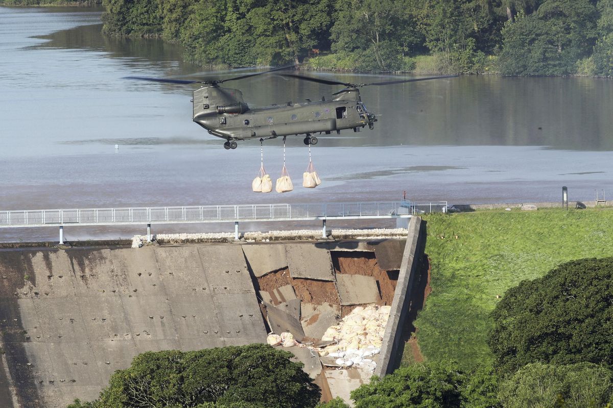 An RAF Chinook helicopter carrying sandbags arrive at the dam at Toddbrook reservoir near the village of Whaley Bridge, central England, Friday Aug. 2, 2019, after it was damaged by heavy rainfall. British police ordered the evacuation of the town of 6,500 people on Thursday over fears that the rain-damaged dam could collapse. (Danny Lawson / AP)