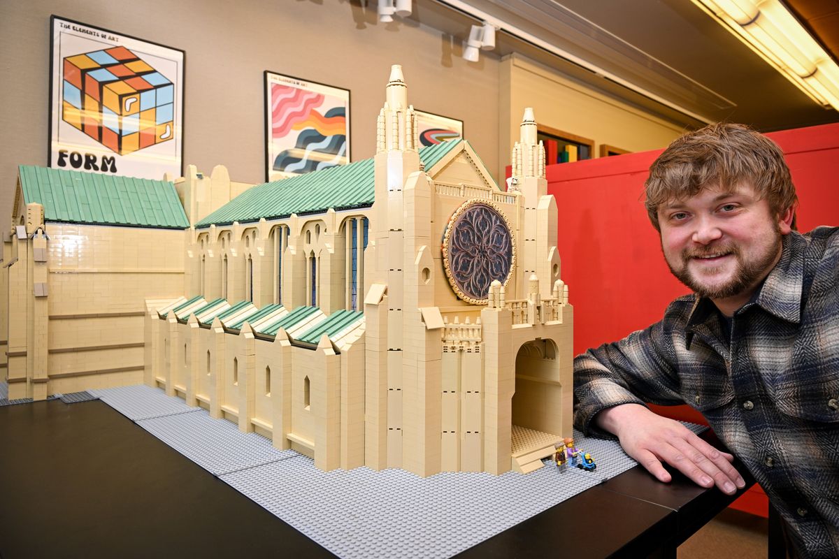 LEGO builder Christian Gill kneels Jan. 6 next to his replica of the Cathedral of St. John the Evangelist, which he is constructing for the Northwest Museum of Arts and Culture exhibit opening this weekend. He is one of several Lego artists creating Spokane’s local landmarks from the toy building blocks for a show called “Brick by Brick: We Built This City.”  (Jesse Tinsley/THE SPOKESMAN-REVIEW)