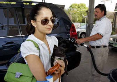 
Angela Noyan, 23, holding her dog, Lola, looks at the gas pump as a station attendant fills her Lexus sport utility vehicle three-quarters full with premium gas for $39.20 at the Majestic Car Wash and Chevron station in Los Angeles. 
 (Associated Press / The Spokesman-Review)