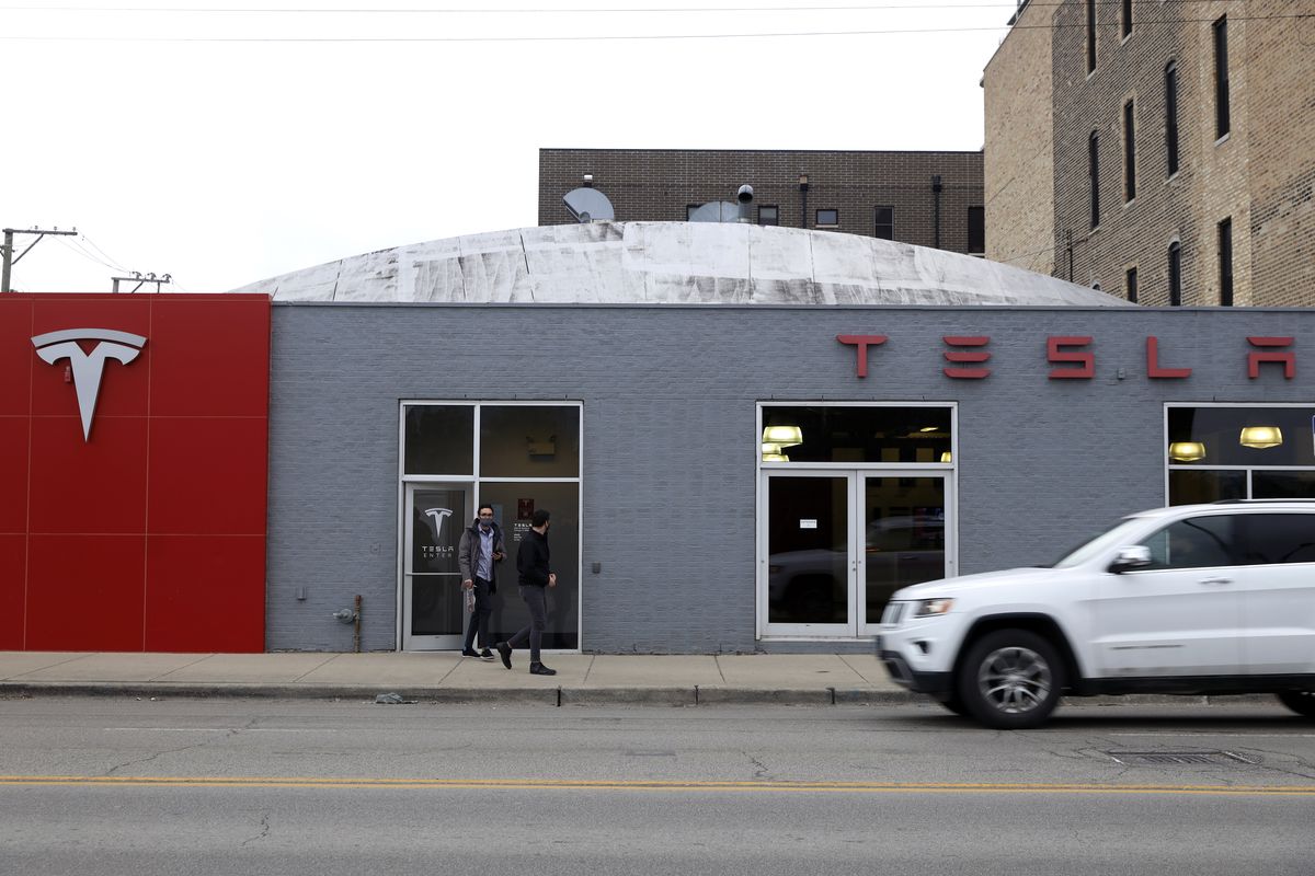 People exit a Tesla Motor showroom in Chicago on Wednesday, March 31, 2021. President Joe Biden outlined a huge $2.3 trillion plan Wednesday to reengineer the nation’s infrastructure in what he billed as “a once in a generation investment in America” that would undo his predecessor’s signature legislative achievement of giant tax cuts for corporations in the process.  (Shafkat Anowar)
