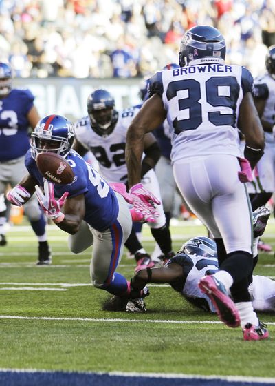 A pass tips off the hands of New York’s Victor Cruz before being intercepted by Brandon Browner. (Associated Press)