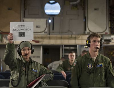 Capt. Noel Carroll, left, of the 446th Reserve Airlift Wing from Joint Base Lewis-McChord holds up a card alerting other unit members of an air emergency during a high-altitude training exercise Sunday.