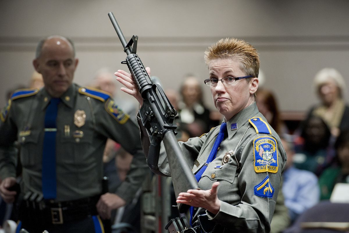 FILE - In this Jan. 28, 2013, file photo, firearms training unit Detective Barbara J. Mattson, of the Connecticut State Police, holds up a Bushmaster AR-15 rifle, the same make and model of gun used by Adam Lanza in the Sandy Hook School shooting, for a demonstration during a hearing of a legislative subcommittee reviewing gun laws, at the Legislative Office Building in Hartford, Conn. Remington, the maker of the rifle used in the Sandy Hook Elementary School shooting has offered some of the victims