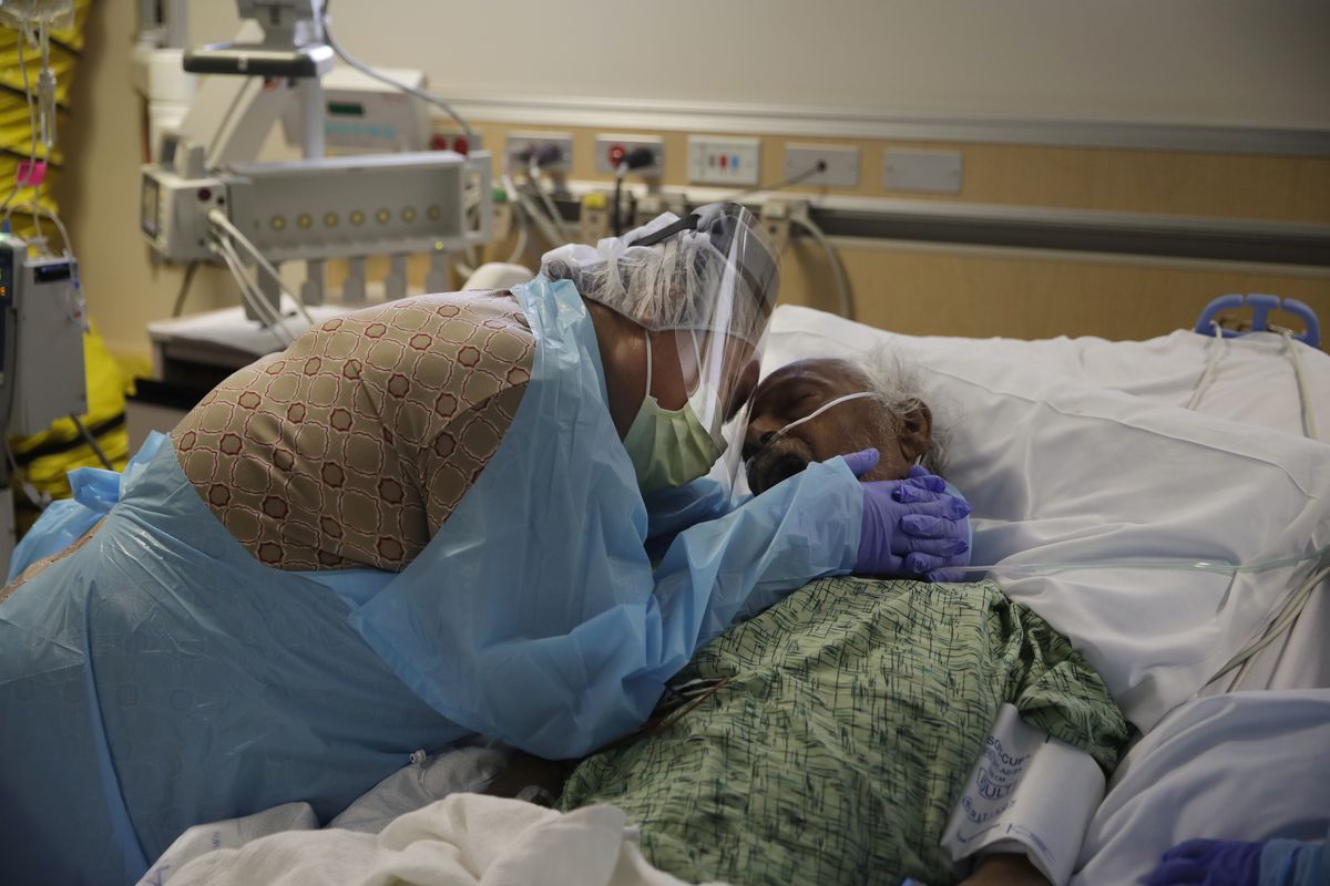 In this July 31, 2020 photo, Romelia Navarro, 64, weeps while hugging her husband, Antonio, in his final moments in a COVID-19 unit at St. Jude Medical Center in Fullerton, Calif. The U.S. death toll from COVID-19 has almost topped 500,000 — a number so staggering that a top health researchers says it is hard to imagine an American who hasn
