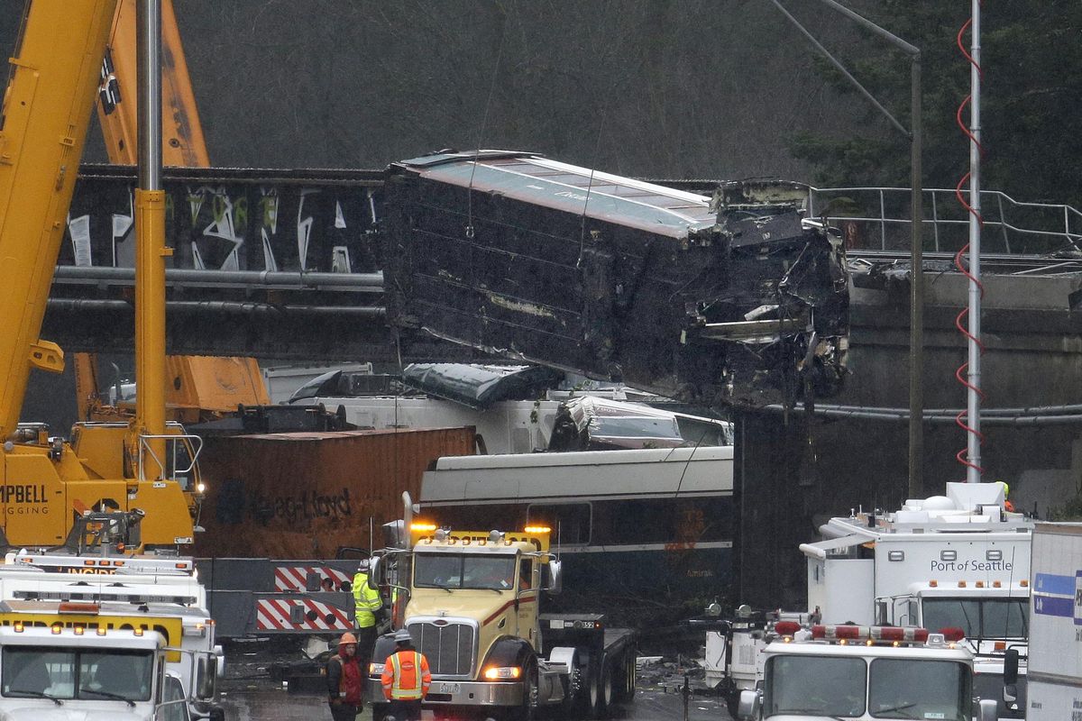 A damaged Amtrak train car is lowered from an overpass at the scene of Monday