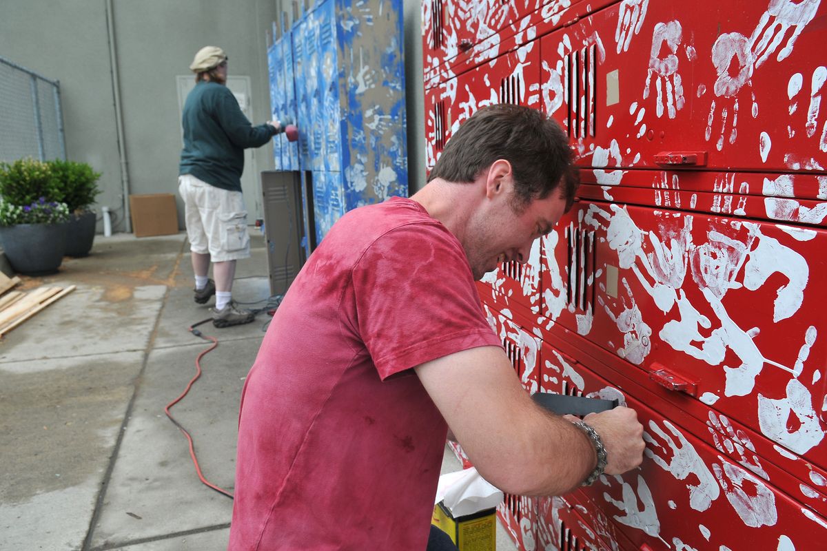 Matt Karasu, right, and Kelly Williams, left, scrape stickers and paint from lockers prior to painting Tuesday outside the site of River Day School, at 116 W. Indiana Ave. (Jesse Tinsley)