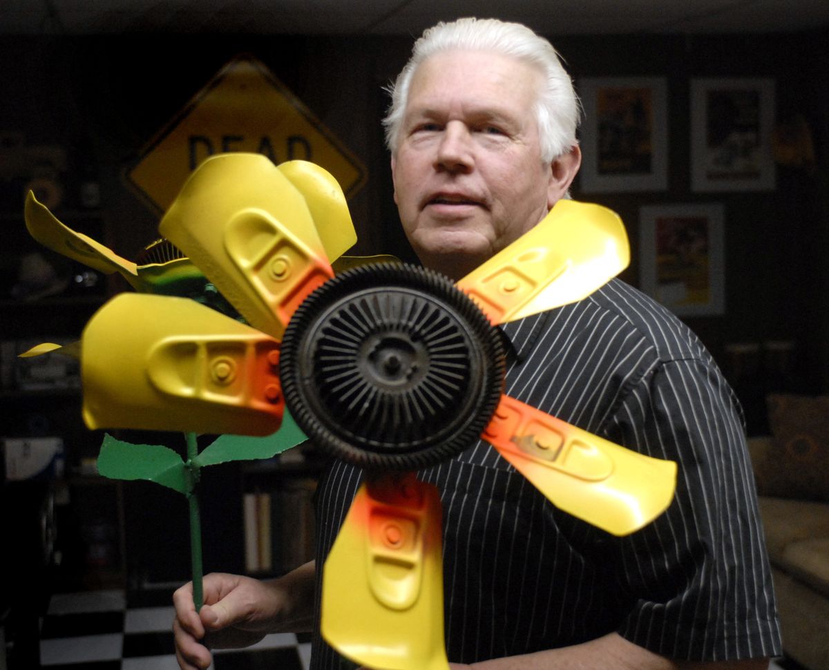 Spokane Valley artist Ray Corder poses with an airbrushed metal flower sculpture he made out of a car motor fan. (J. Rayniak / The Spokesman-Review)