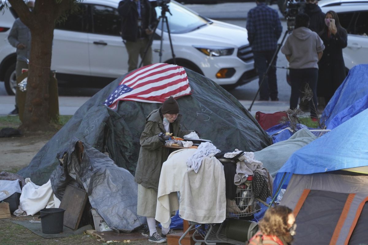 FILE - In this March 24, 2021, file photo a woman eats at her tent at the Echo Park homeless encampment at Echo Park Lake in Los Angeles. California Gov. Gavin Newsom announced a $12 billion plan Tuesday, May 11 to confront the state