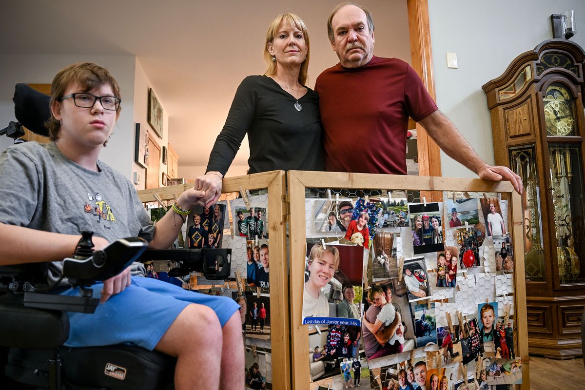 The family of 17-year-old Erik Edge – his brother, Zack, left, and his parents, Sara and Mark – pose at their home Monday with the photo display of Erik from his funeral. Erik died after a reaction to anesthesia during a routine wisdom tooth removal. The parents allege the oral surgeon chose to play two roles by administering anesthesia while also performing surgery.  (Kathy Plonka/The Spokesman-Review)