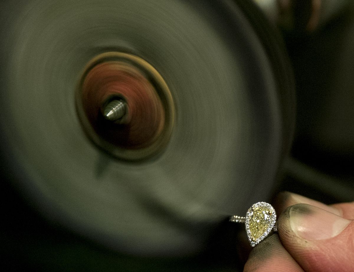 Denver Toone polishes a natural pear-shaped yellow diamond ring on Saturday at Jewelry Design Center in Spokane. (Tyler Tjomsland)