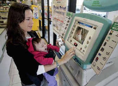 
Jesse Eisenberg of New Yorkuses a digital photo kiosk to print a picture from her digital camera of her 12-week old daughter Shea. 
 (Associated Press / The Spokesman-Review)