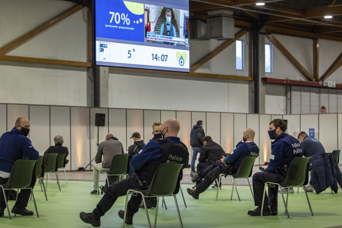 In this March 4, 2021 photo, police officers and others sit in a waiting zone after receiving their COVID-19 vaccine at the Brussels Expo center in Brussels. In both the U.S. and the EU, officials are struggling with the same question: how to boost vaccination rates to the max and end a pandemic that has repeatedly thwarted efforts to control it. In the European Union, officials in many places are requiring people to show proof of vaccination, a negative test or recent recovery from COVID-19 to participate in everyday activities — even sometimes to go to work.  (Olivier Matthys)
