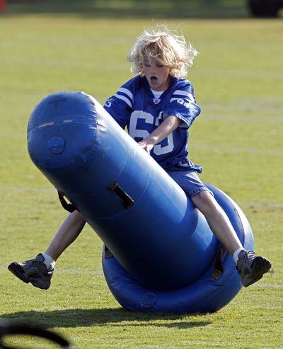 Jeffrey Saturday, 10, son of Indianapolis Colts center Jeff Saturday,  plays on a blocking dummy as the team practiced during the NFL team's football training camp in Anderson, Ind., Monday, Aug. 8, 2011. (Michael Conroy / Associated Press)