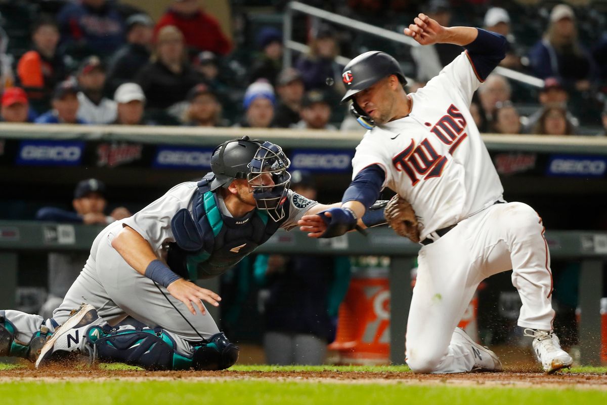 Seattle Mariners catcher Cal Raleigh, left, tags out Minnesota Twins