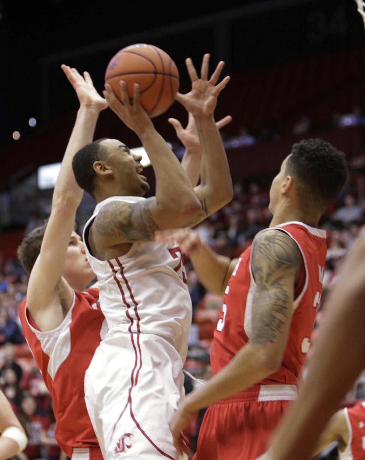 Washington State Cougars guard DaVonte’ Lacy looks for a first-half basket between a pair of Utah Utes in Pullman. (Associated Press)