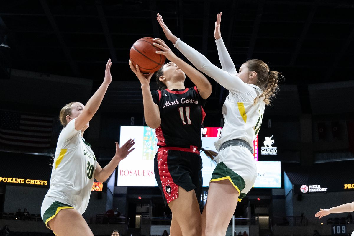 North Central’s Kamari Vaile (11) lines up a shot as Shadle Park’s McKenzie Duncan (11) and Taylor Stoddard (20) defend during the Groovy Shoes high school basketball game, Wed., Dec. 18, 2024, at the Spokane Veterans Arena.  (COLIN MULVANY)