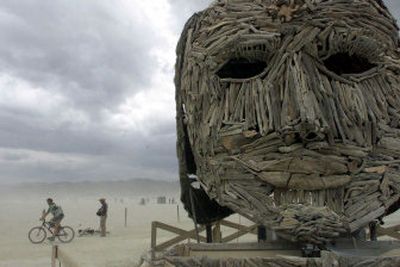 
Attendees of the Burning Man Festival in the Black Rock Desert near Gerlach, Nev., in 2000, pass by one of the faces in the sculpture titled 