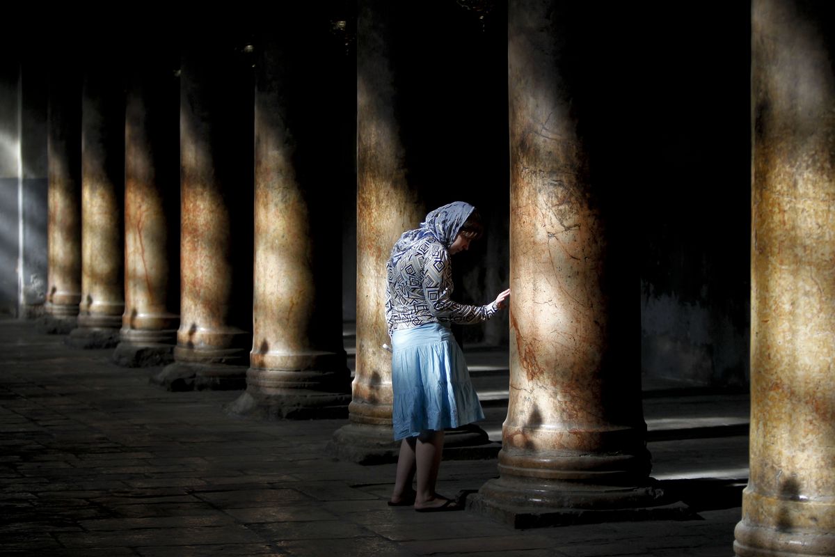 A Russian tourist touches a column inside the Church of the Nativity, where  Christians believe Jesus Christ was born, in the West Bank town of Bethlehem, on Thursday.  (Associated Press)