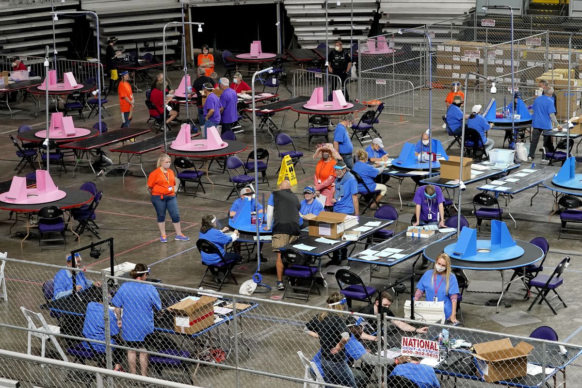 In this May 6, 2021 photo, Maricopa County ballots cast in the 2020 general election are examined and recounted by contractors working for Florida-based company, Cyber Ninjas at Veterans Memorial Coliseum in Phoenix. Arizona’s largest county has approved nearly $3 million for new vote-counting machines to replace those given to legislative Republicans for a partisan review of the 2020 election. The GOP-controlled Maricopa County Board of Supervisors said Wednesday, July 14, 2021 that the machines were compromised because they were in the control of firms not accredited to handle election equipment. (Matt York)