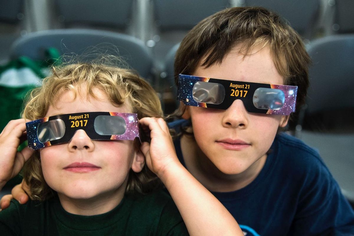 Maggie, 4, and Sam Thompson, 7, try on their new solar eclipse glasses after class at the South Hill Library on July 26, 2017. The eye protection was passed out after the room of children and parents learned how to view the Aug. 21 eclipse that will cross over Spokane and the Northwest. (Dan Pelle / The Spokesman-Review)
