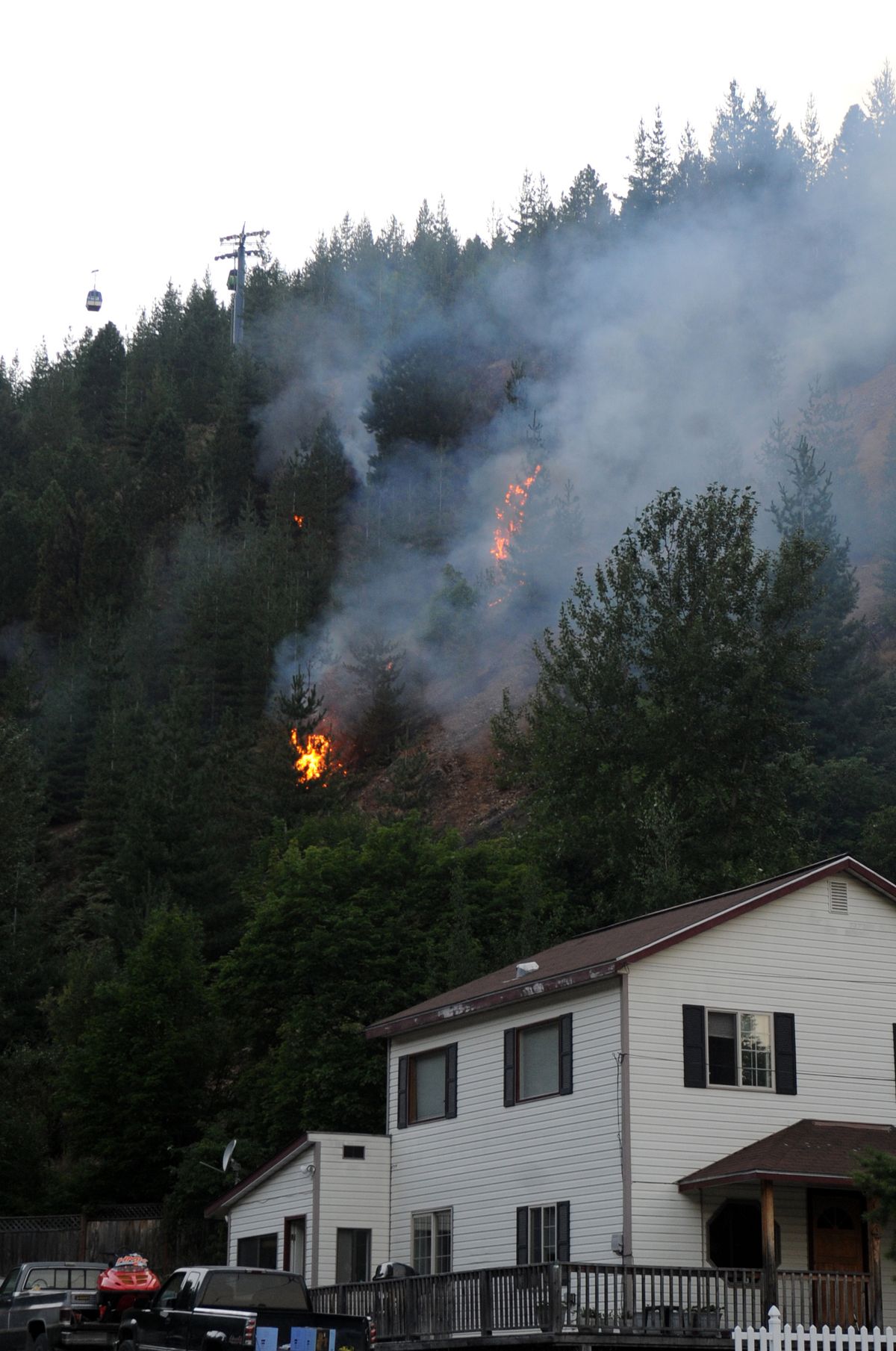 Hot spots flare up above homes near Kellogg on Wednesday. A wildfire started behind some homes there and rushed up the steep hillsides Wednesday afternoon, briefly forcing authorities to talk about evacuation plans. By nightfall, the fire’s spread was slowed. (Jesse Tinsley)