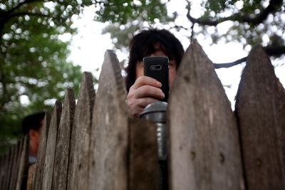 An observer takes a picture with his  phone from behind a fence on the grassy knoll at Dealey Plaza in Dallas on Saturday,  the 45th anniversary of the assassination of President John F. Kennedy. (Associated Press / The Spokesman-Review)