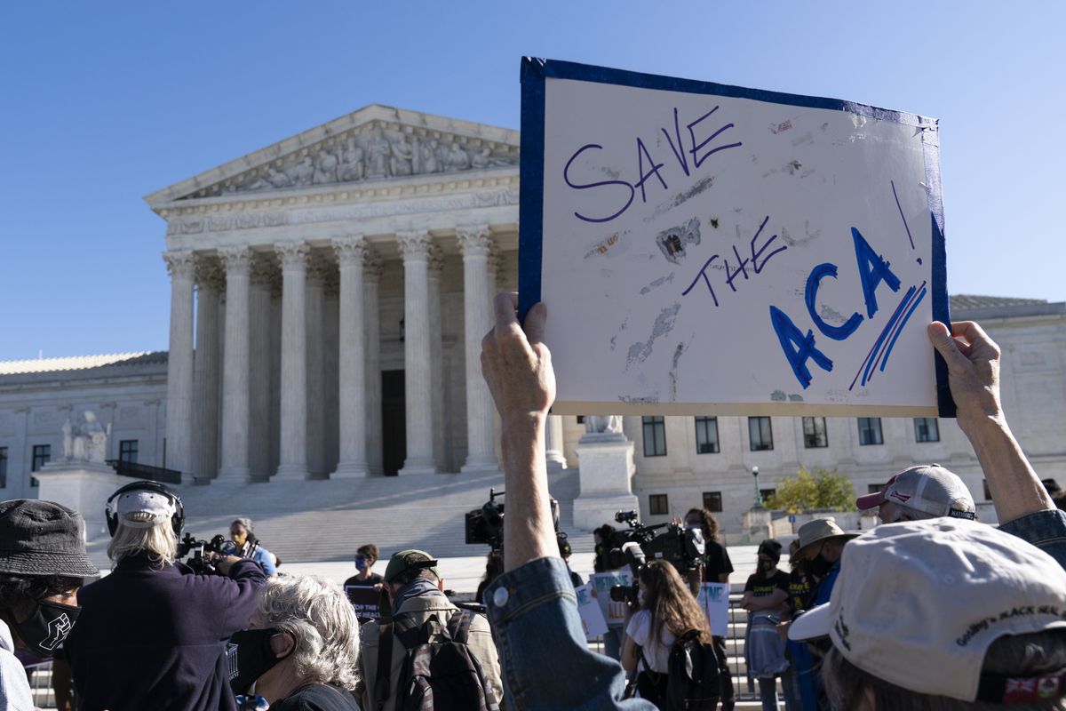 A demonstrator holds a sign in front of the U.S. Supreme Court as arguments are heard about the Affordable Care Act, Tuesday, Nov. 10, 2020, in Washington. (Alex Brandon)