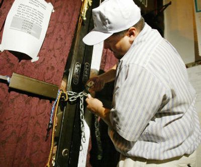 
On Thursday, Roberto Lopez, helped by people on the outside, chains the front door inside Adalberto United Methodist Church where Elvira Arellano has taken refuge to avoid deportation.
 (Associated Press / The Spokesman-Review)