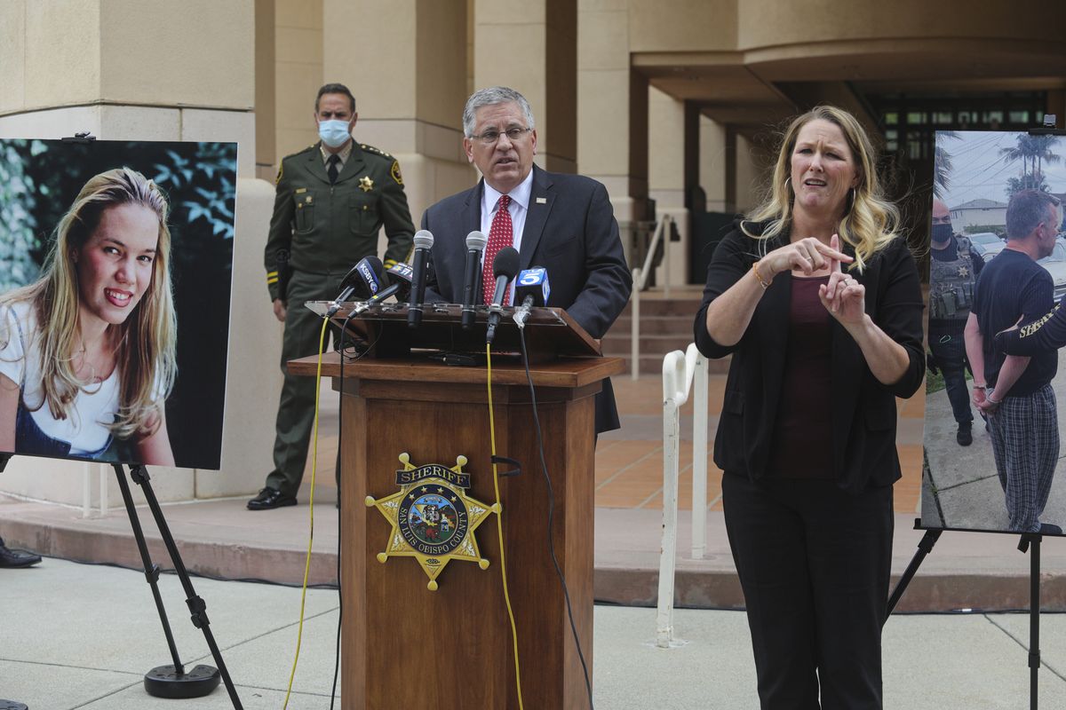 In this April 13, 2021 photo, Cal Poly President Jeffrey Armstrong, center, speaks during a news conference in San Luis Obispo, Calif. At left is a photo of student Kristin Smart. A California judge is expected to rule Wednesday, Sept. 22, 2021, whether a father and son face trial on charges related to the disappearance 25 years earlier of Smart.  (David Middlecamp)