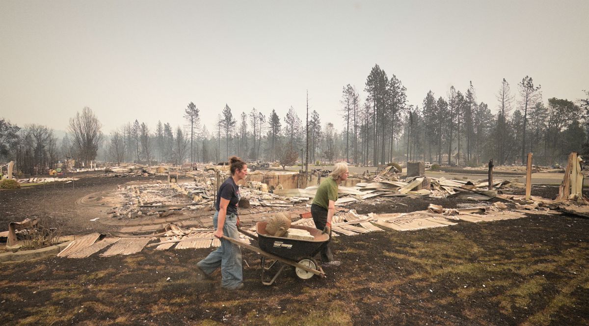 Erin Conley and Heidi Dickinson remove parts of a statue Sunday from Conley’s home on West Park West Court that was lost in the wildfire. Conley was a second-generation owner of the home. (Brian Plonka/The Spokesman-Review)