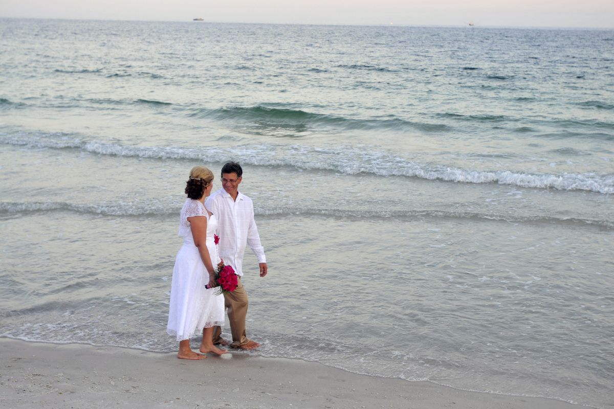 Rion Bowers, right, and Gidget Miller of Tucson, Ariz., walk along the beach after being married earlier this month  on Pensacola Beach, Fla. Bowers and Miller were determined to exchange vows with the backdrop of a soft, pink beach sunset and turquoise waters – even with the outer edges of the Gulf oil spill lurking just offshore.  (Associated Press)