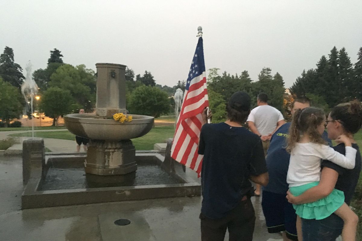 Andrew Perl holds an American flag in front of a Confederate memorial on Thursday, Aug. 17, 2017, in Helena, Mont., as Marlee Hanson looks on while holding her daughter. About two dozen people gathered to protest after city workers made initial preparations to dismantle the granite fountain commissioned by the Daughters of the Confederacy more than a century ago. (Matt Volz / Associated Press)