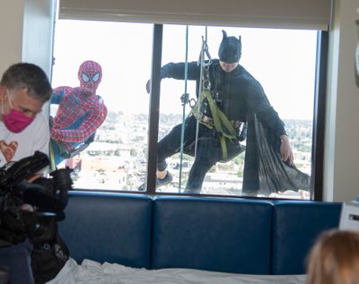 Two costumed window washers dressed as Spider-man and Batman appear Wednesday at a window of a room at the Providence Sacred Heart Children’s Hospital. (Jesse Tinsley/The Spokesman-Review)