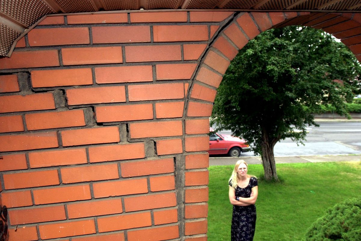 Cracks running from top left to lower right and along the curved brick edge at right show damage from an earthquake in 2001. Dianna Burdick stands in July 2001 in front of her Corbin Park home which suffered fairly extensive damage to brick areas like her entry, the chimney and the garage area from an earthquake in Spokane.  (Christopher Anderson/The Spokesman-Review)